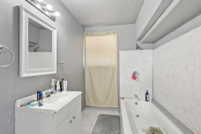 full bath with marble finish floor, vanity, bathtub / shower combination, and a textured wall