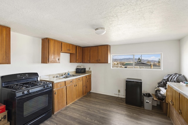 kitchen featuring a sink, brown cabinets, black appliances, and dark wood finished floors