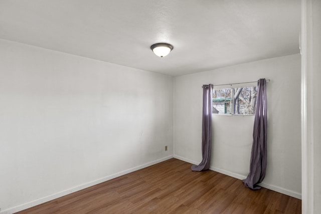 unfurnished room with baseboards and wood finished floors