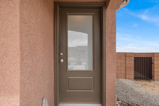 property entrance with fence and stucco siding