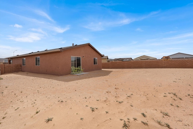 rear view of house featuring a patio area, a fenced backyard, and stucco siding