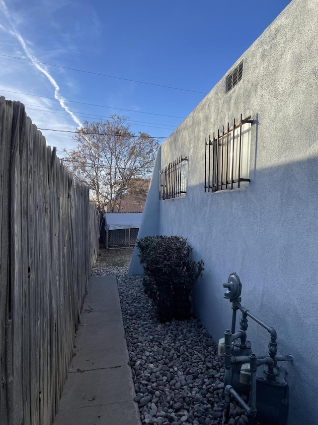 view of side of property featuring fence and stucco siding