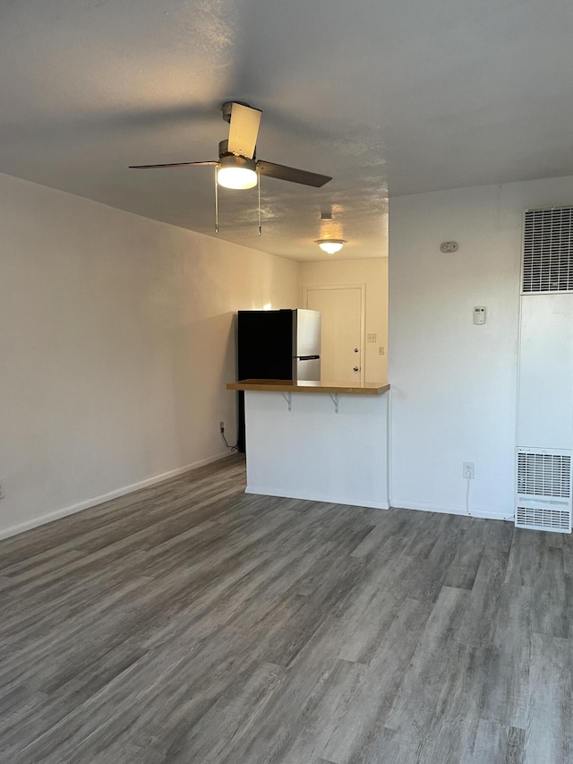 unfurnished living room featuring a heating unit, wood finished floors, a ceiling fan, and baseboards