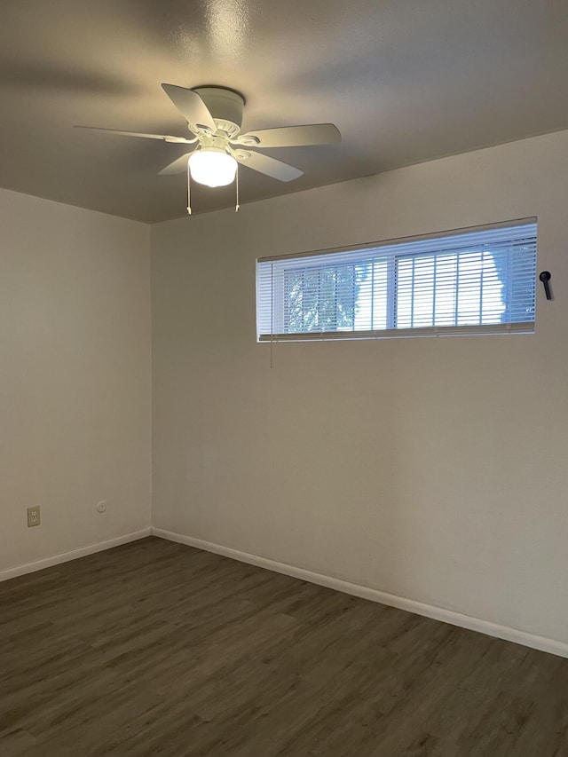 spare room featuring dark wood-type flooring, ceiling fan, and baseboards