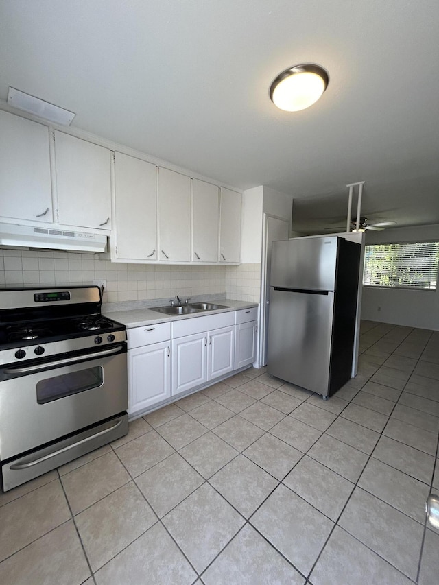 kitchen with under cabinet range hood, stainless steel appliances, a sink, light countertops, and decorative backsplash