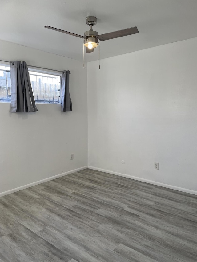 empty room with a healthy amount of sunlight, baseboards, and wood finished floors