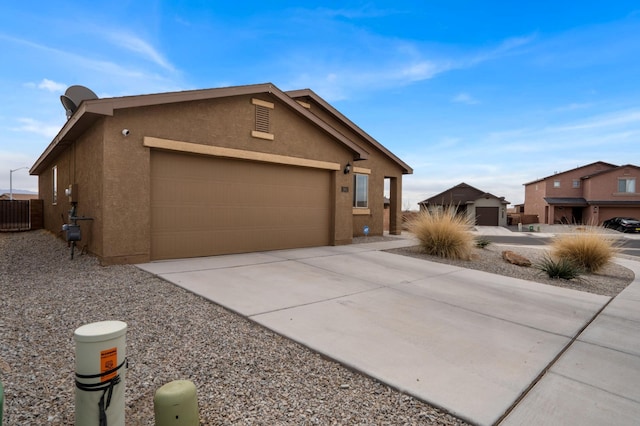 view of front facade with stucco siding, an attached garage, concrete driveway, and fence