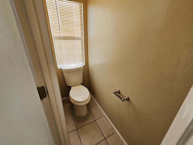 bathroom featuring tile patterned flooring, toilet, and baseboards