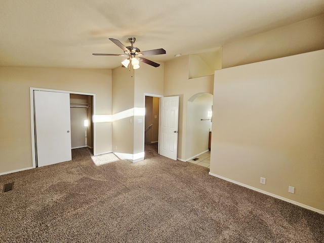 unfurnished bedroom featuring visible vents, baseboards, arched walkways, carpet flooring, and lofted ceiling