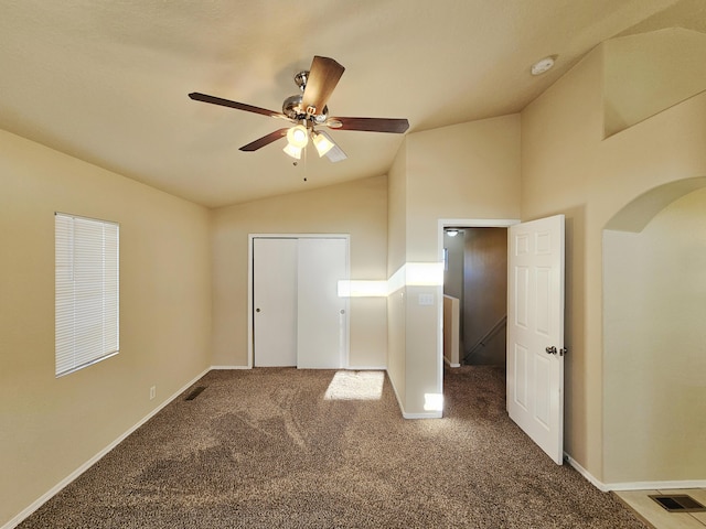 unfurnished bedroom with arched walkways, baseboards, lofted ceiling, and carpet floors