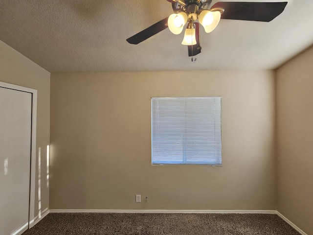 spare room featuring dark carpet, a textured ceiling, baseboards, and a ceiling fan