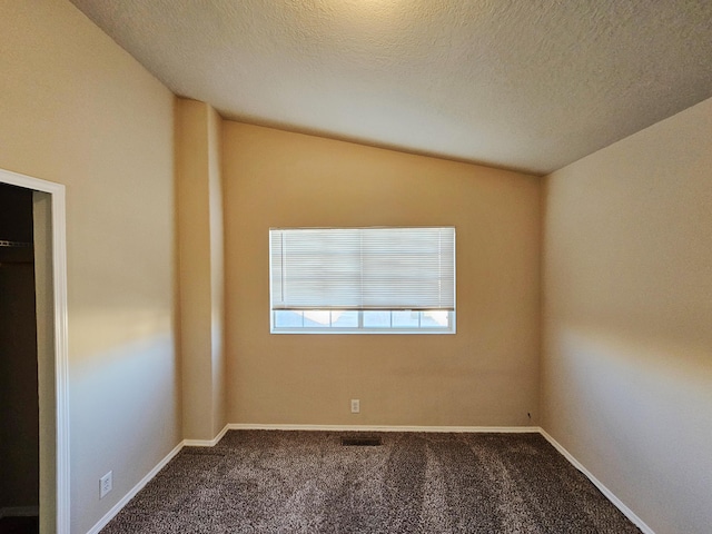 unfurnished room featuring carpet flooring, a textured ceiling, baseboards, and vaulted ceiling