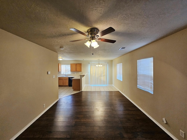 unfurnished living room featuring visible vents, ceiling fan with notable chandelier, baseboards, and light wood-style floors