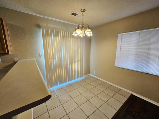 unfurnished dining area with light tile patterned floors, visible vents, a textured ceiling, and an inviting chandelier