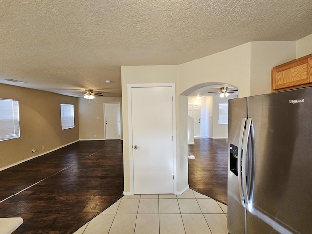 kitchen with arched walkways, ceiling fan, light wood finished floors, and stainless steel refrigerator with ice dispenser