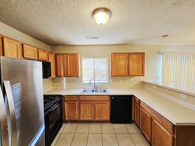 kitchen with brown cabinetry, visible vents, black appliances, and a sink