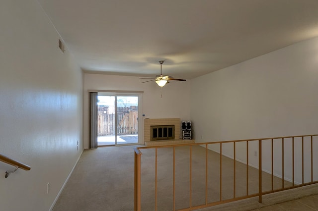 unfurnished living room with visible vents, carpet floors, a fireplace, baseboards, and ceiling fan