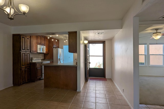 kitchen with baseboards, light tile patterned floors, ceiling fan with notable chandelier, a peninsula, and white appliances