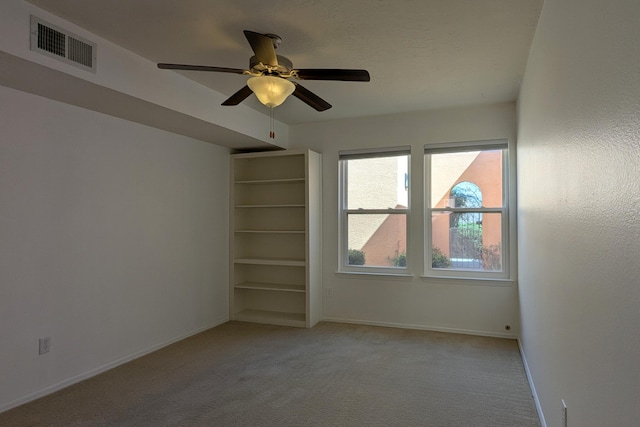 spare room featuring visible vents, light colored carpet, baseboards, and ceiling fan