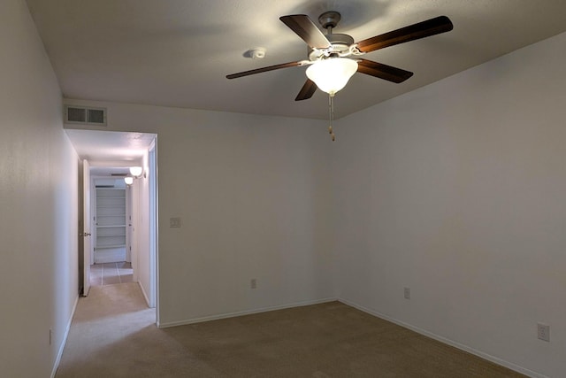 empty room featuring light carpet, visible vents, ceiling fan, and baseboards