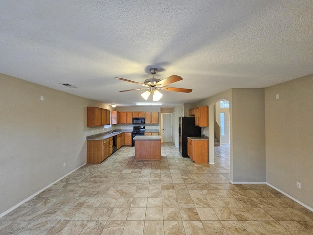 6619 Country Hills Ct NW, Albuquerque, NM 87114 - kitchen with visible vents, black appliances, a center island, brown cabinetry, and baseboards