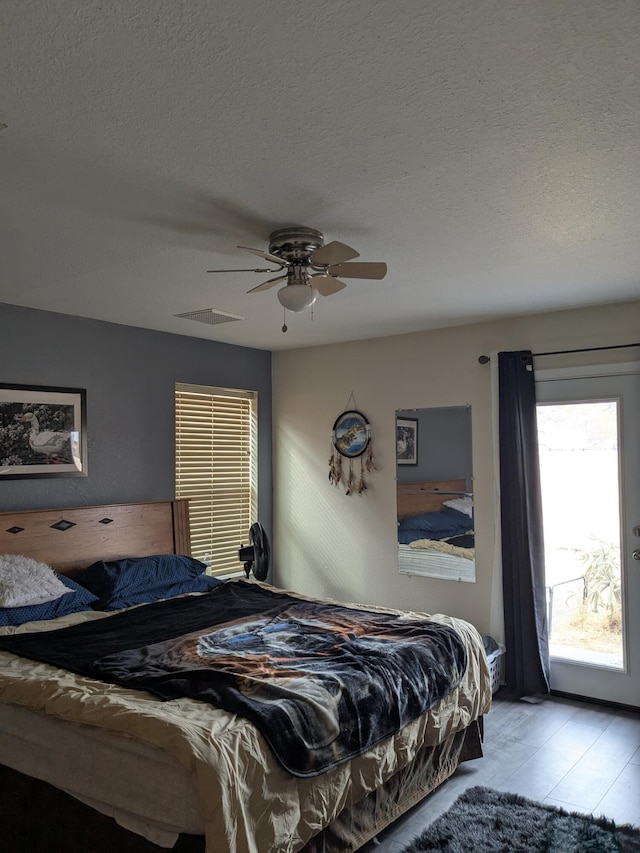 bedroom featuring access to outside, visible vents, ceiling fan, and a textured ceiling