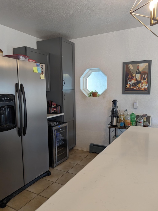 kitchen featuring light tile patterned floors, stainless steel fridge, wine cooler, light countertops, and a textured ceiling