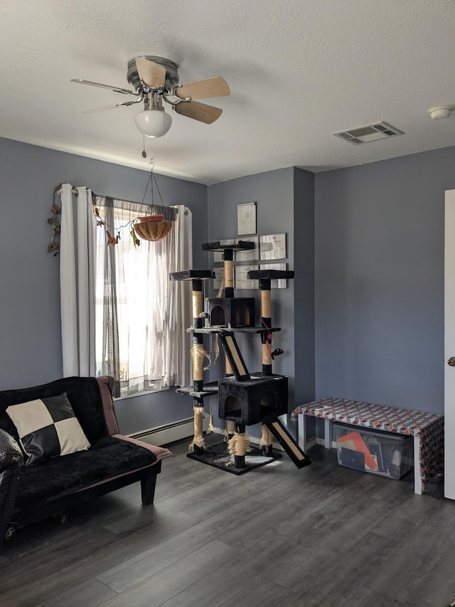 living area featuring a baseboard radiator, visible vents, ceiling fan, a textured ceiling, and wood finished floors