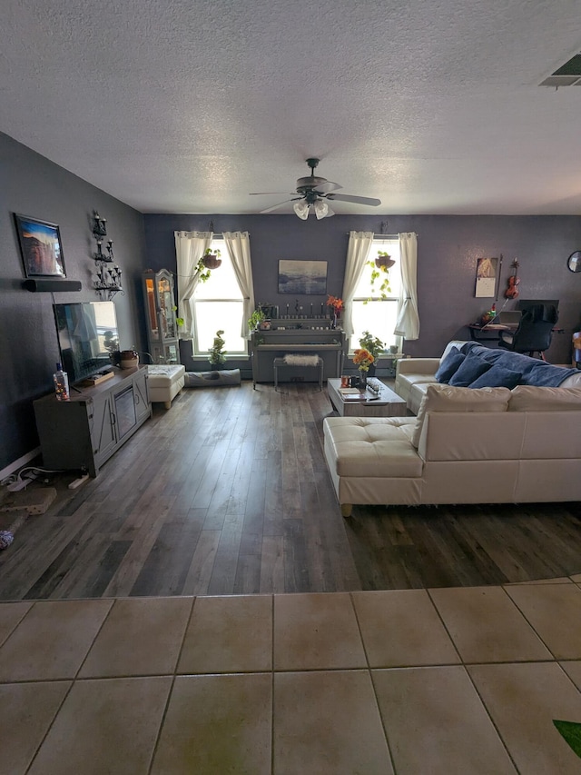 living room with ceiling fan, a textured ceiling, wood finished floors, and visible vents