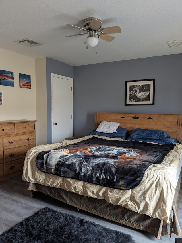 bedroom with a ceiling fan, visible vents, and wood finished floors