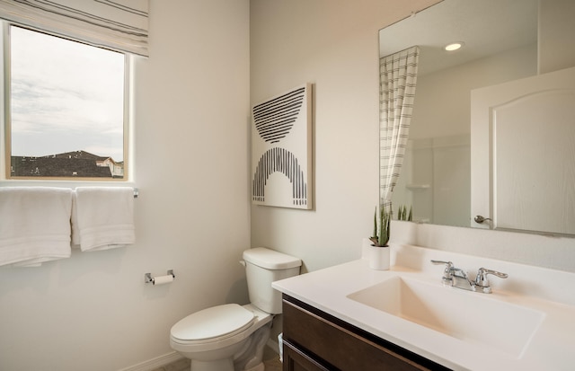 bathroom with baseboards, vanity, and toilet