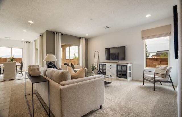 living room with a textured ceiling, visible vents, a wealth of natural light, and recessed lighting