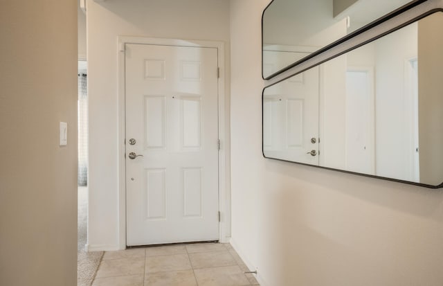 doorway featuring light tile patterned floors and baseboards