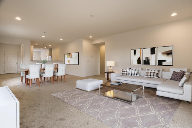 living room featuring baseboards, recessed lighting, and light colored carpet