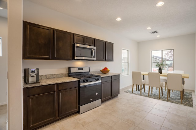 kitchen with recessed lighting, stainless steel appliances, visible vents, dark brown cabinets, and light stone countertops