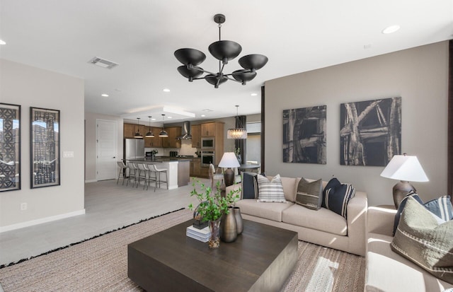 living area featuring visible vents, baseboards, a chandelier, light wood-type flooring, and recessed lighting