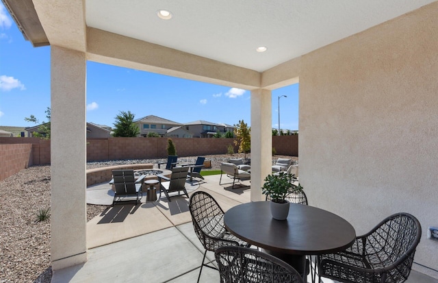 view of patio featuring an outdoor fire pit, outdoor dining area, and a fenced backyard