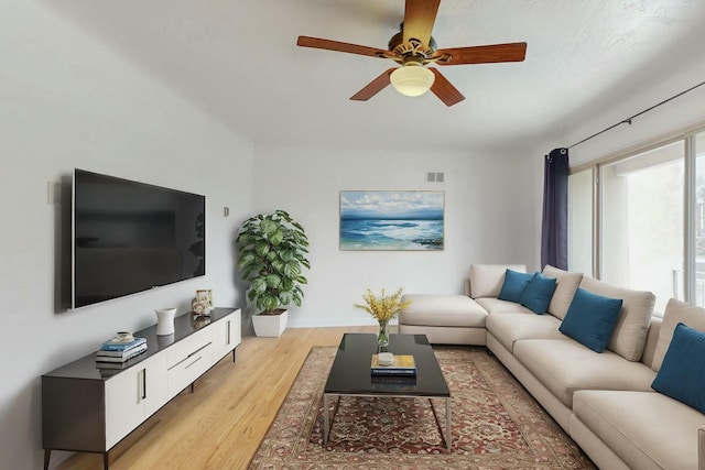 living room featuring visible vents, ceiling fan, and light wood finished floors