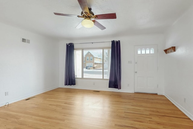 spare room featuring a ceiling fan, visible vents, light wood-type flooring, and baseboards