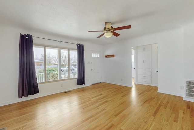 empty room with light wood-style floors, visible vents, and baseboards