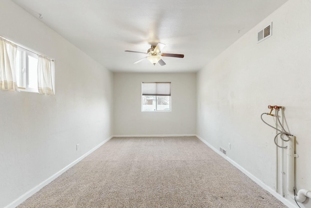 carpeted empty room with visible vents, baseboards, and a ceiling fan