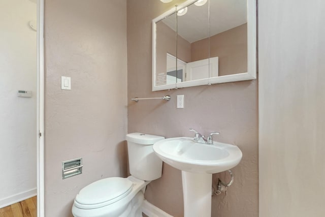 bathroom featuring toilet, baseboards, and wood finished floors