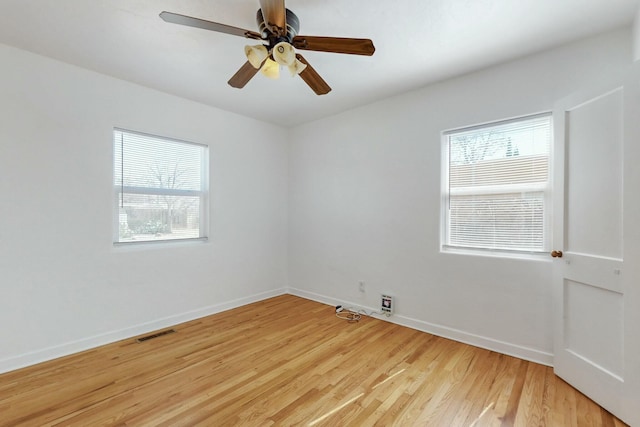 spare room featuring a wealth of natural light, visible vents, baseboards, and light wood-style floors