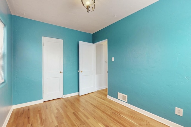 unfurnished bedroom with visible vents, baseboards, and wood finished floors