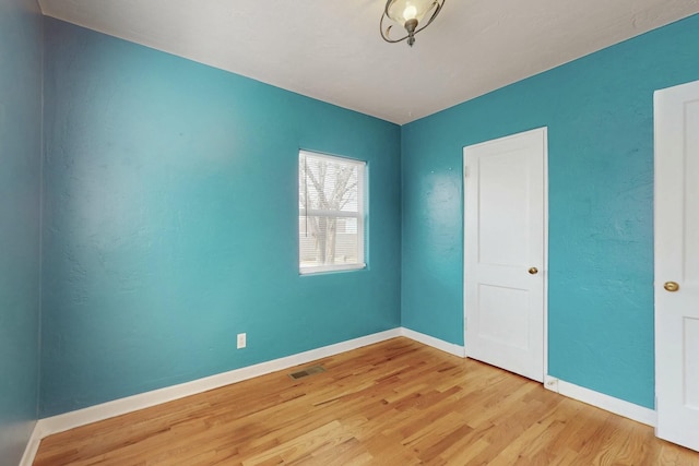 empty room featuring visible vents, baseboards, and wood finished floors