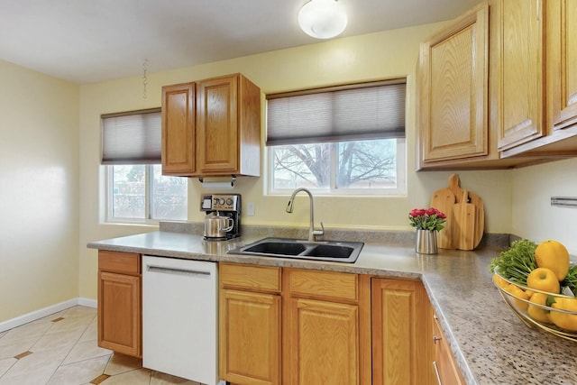 kitchen featuring baseboards, light countertops, light tile patterned floors, white dishwasher, and a sink