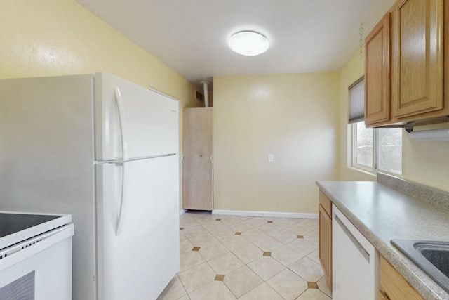 kitchen featuring white appliances, baseboards, light tile patterned flooring, a sink, and light countertops