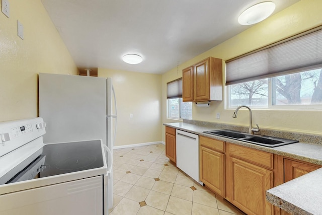 kitchen with baseboards, light countertops, light tile patterned flooring, white appliances, and a sink