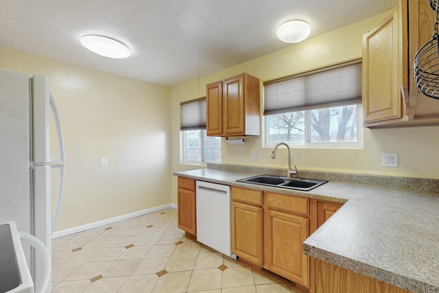 kitchen with a sink, white appliances, light countertops, light tile patterned floors, and baseboards