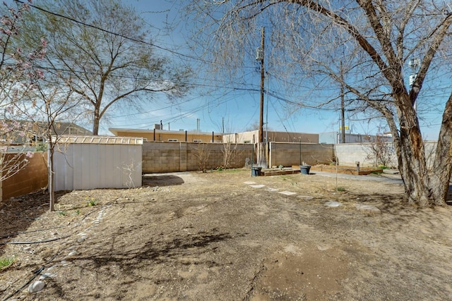 view of yard featuring an outdoor structure, fence, and a shed